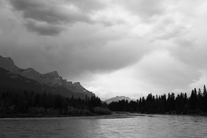 a body of water near the mountains under cloudy skies