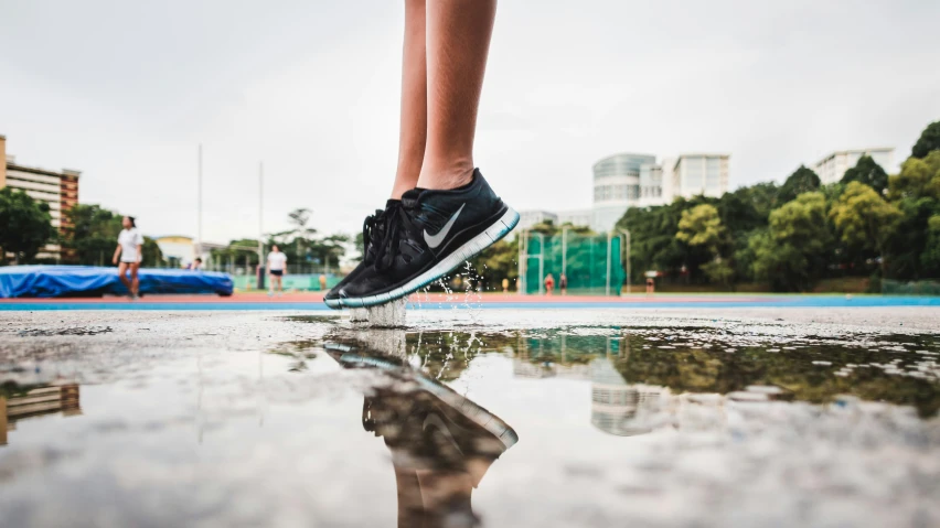 a woman's feet standing on the ground in the rain