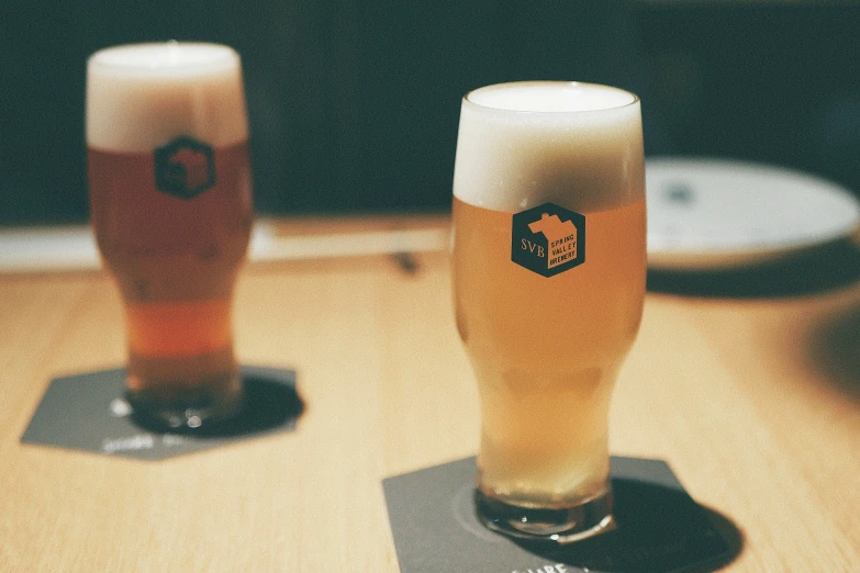 two beers sit in glass mugs on the table