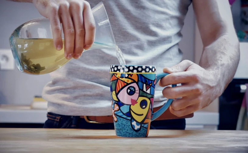 someone pours tea into a colorful coffee cup