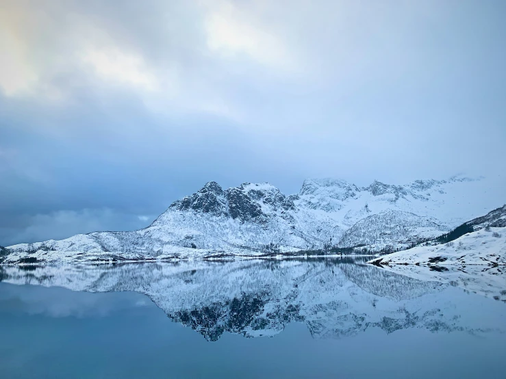 the snow covered mountains are reflected in the water