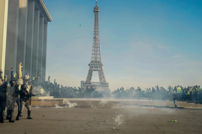 smoke rises from the ground as people look on in front of the eiffel tower