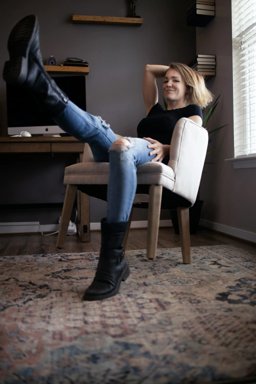 a woman is smiling and leaning forward on a chair with legs up