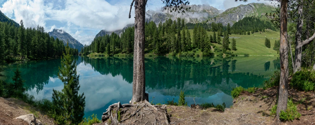 view from a mountain to the lake, with trees and mountains in the distance