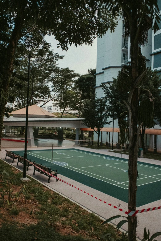 a tennis court, benches and trees on a sunny day