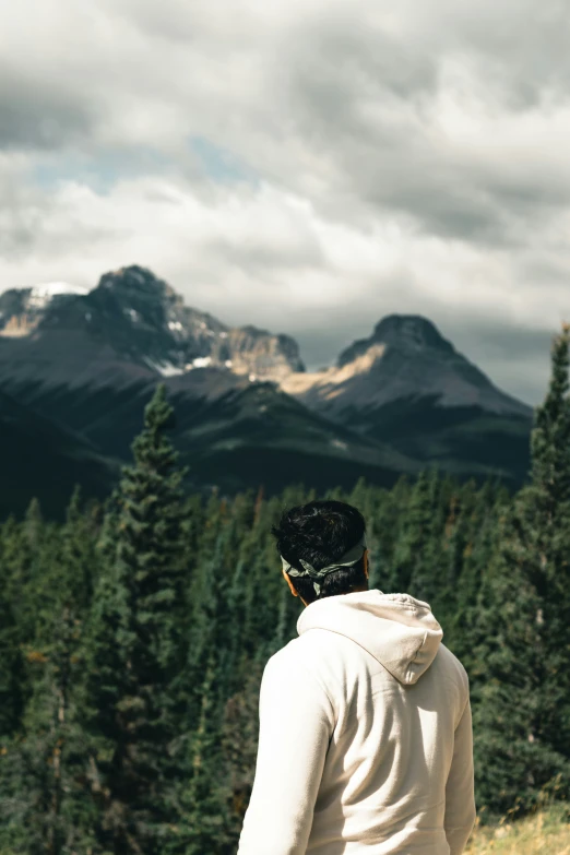 a man standing on a mountain looking over trees