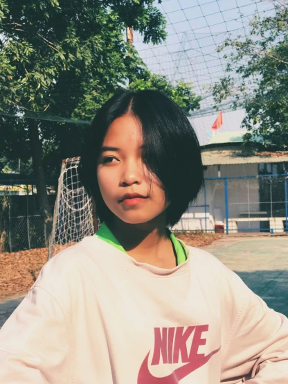 a girl is wearing a nike sweater and posing in front of a goal