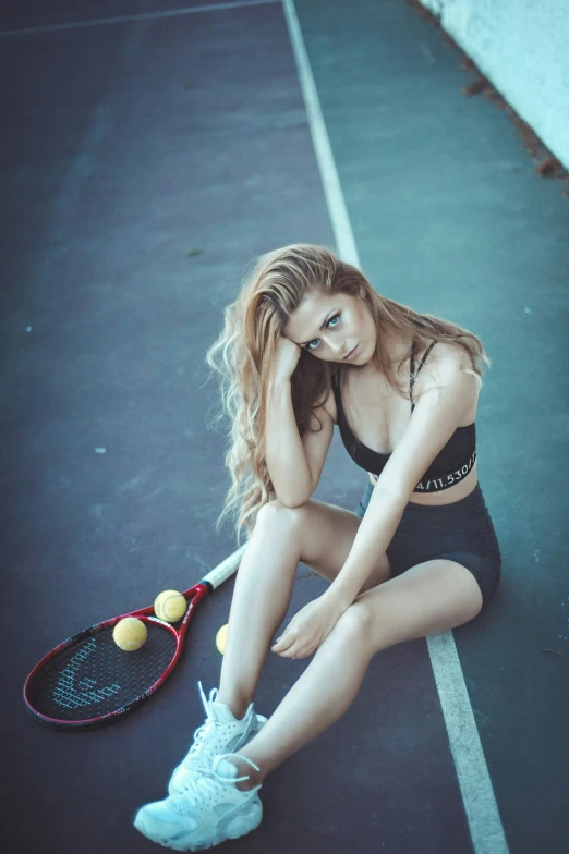 a woman sitting on a tennis court with a racket