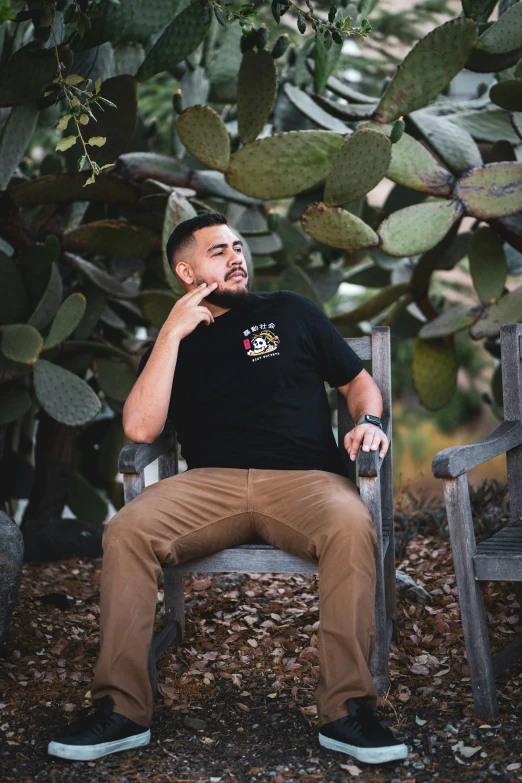 a man smoking a cigarette sitting on a bench next to a cactus