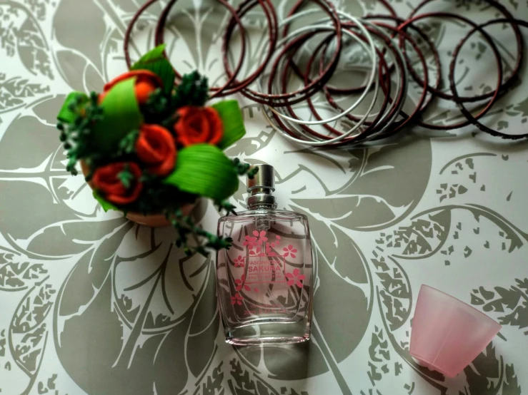 a table with perfume bottles and pink glasses and rings