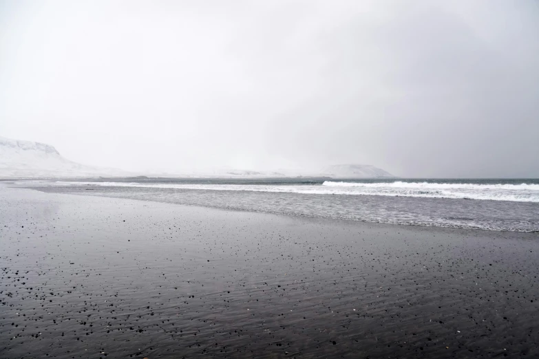 the water and sand has waves coming in towards the shore