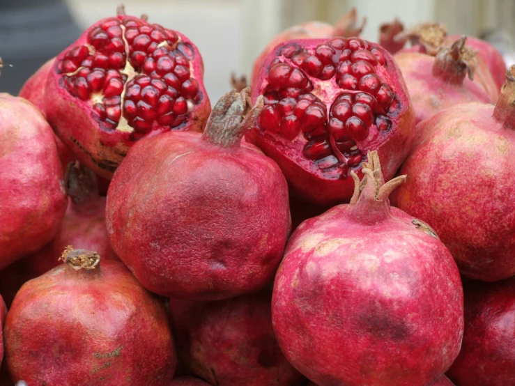 a pile of pomegranates with leaves and one whole pomegranate