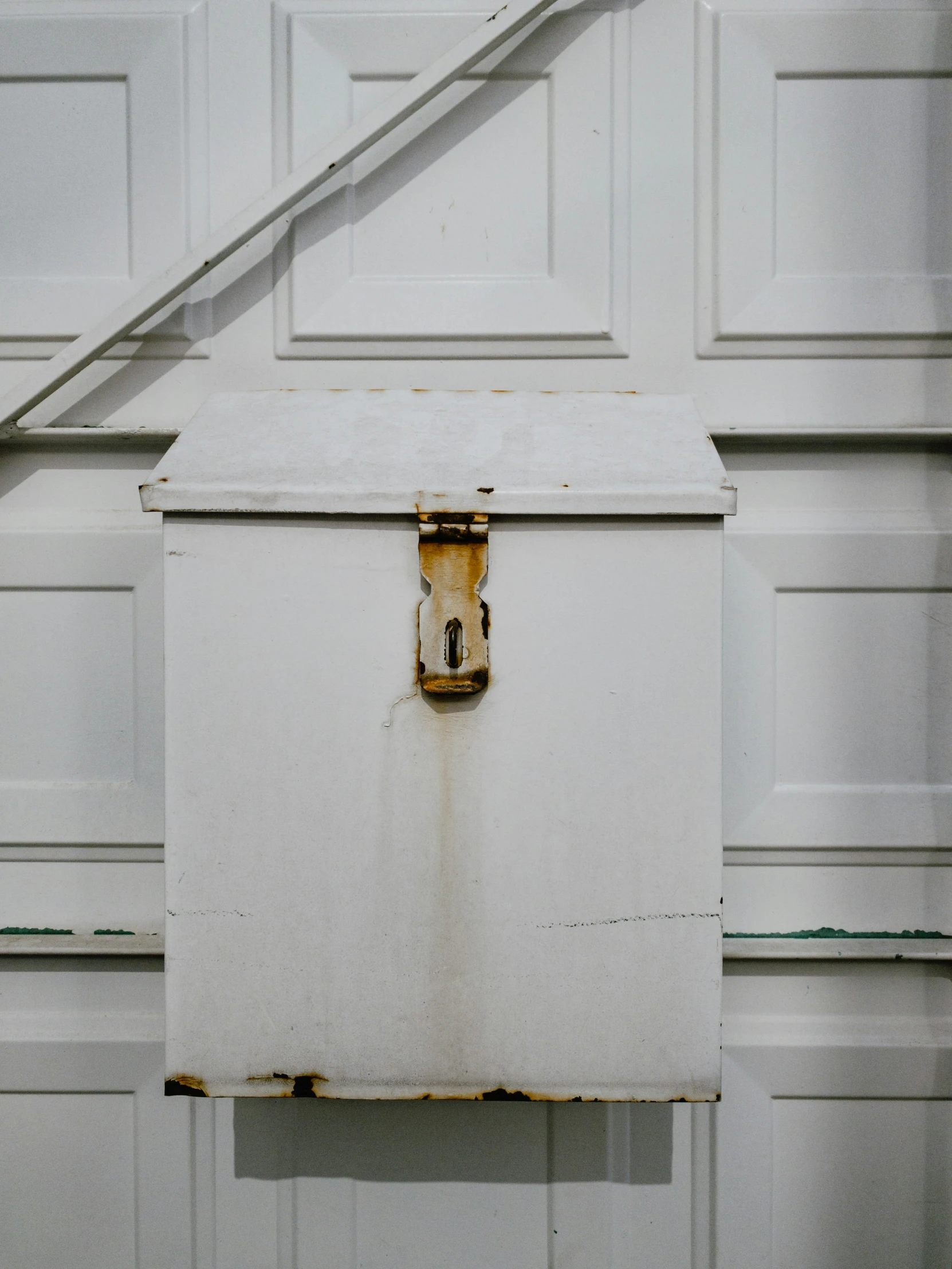 an old, rusty steel latch on a white box