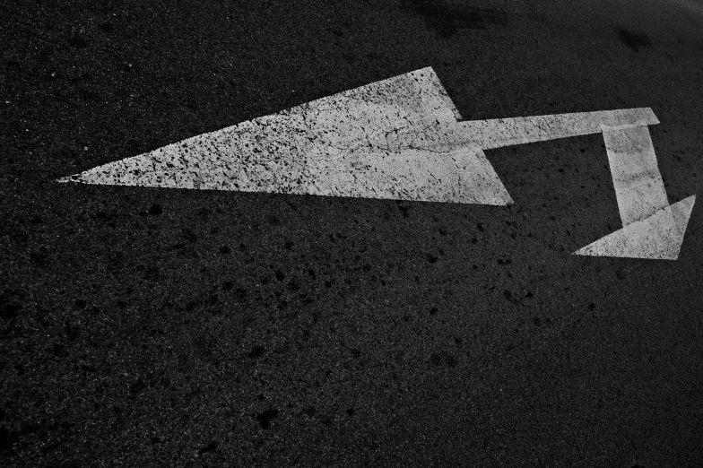 a white street sign and a arrow drawn on a pavement