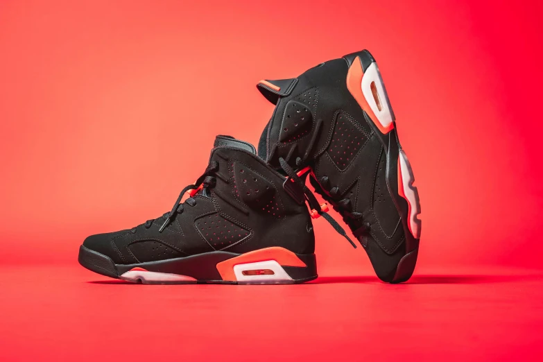 a pair of black and orange sneakers on a red background