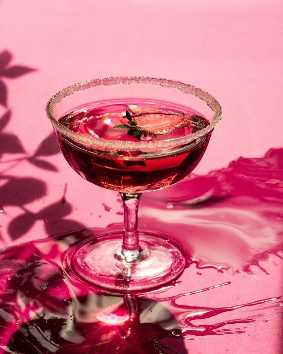 wine cocktail with water in a glass sitting on a pink background