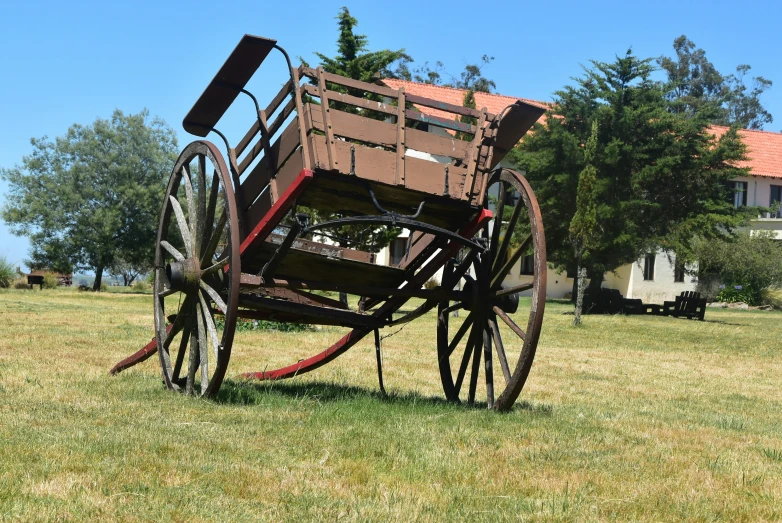 a brown old fashioned wooden cart on some grass