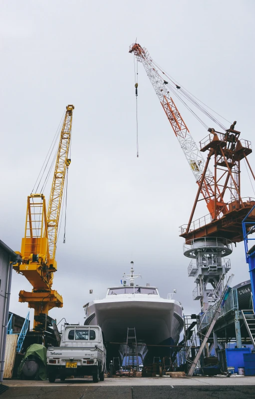 a boat sitting in a warehouse next to some cranes