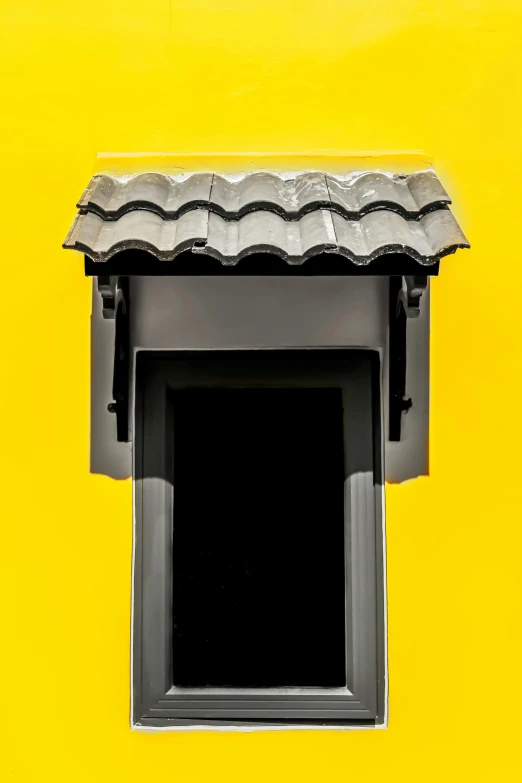 a small window on a yellow wall with gray roof