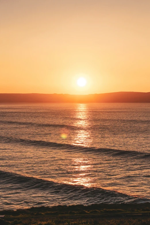 a sunset over the ocean with birds flying in the air