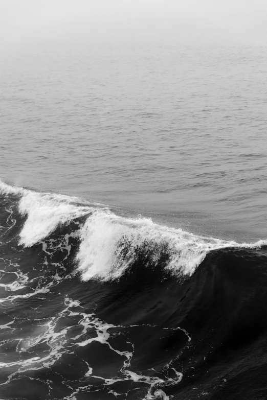 black and white image of person surfing the ocean