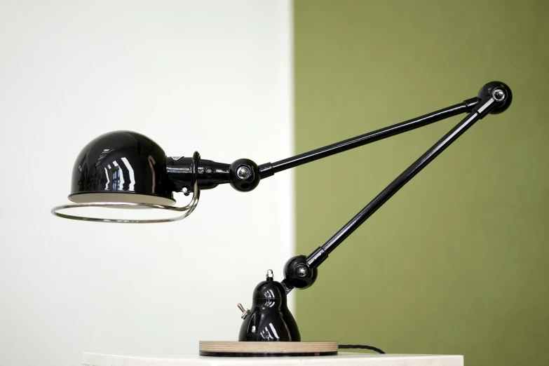 a desk lamp sitting up against a green wall