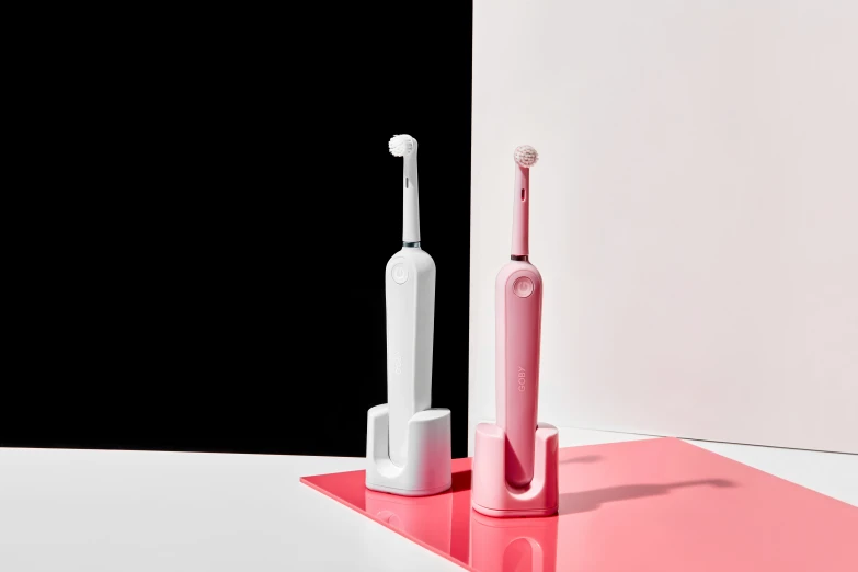 the pink electric toothbrush and an additional one are placed next to each other