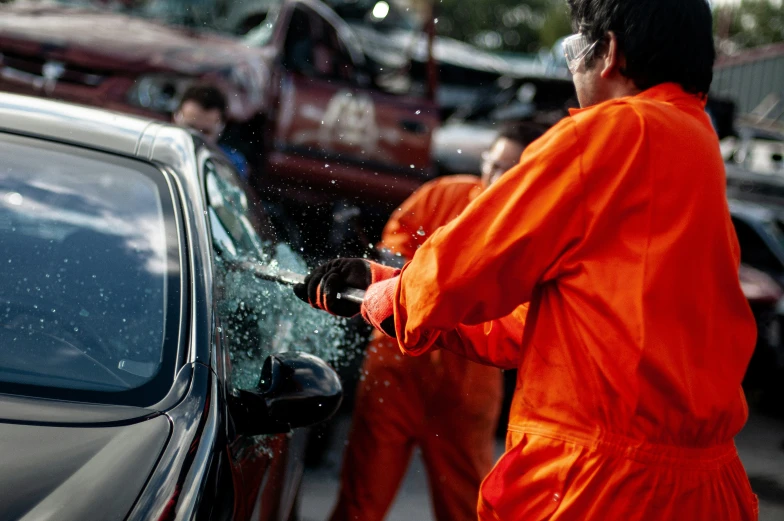 a woman in orange is using a water hose