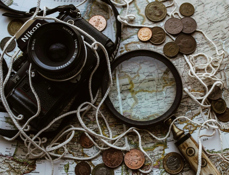 a camera laying on top of a world map and several coins