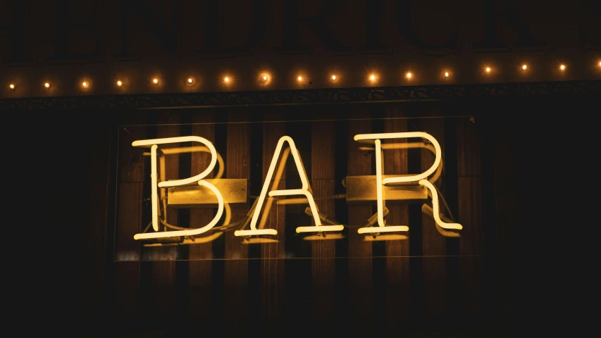 a neon sign saying bar on a brick wall