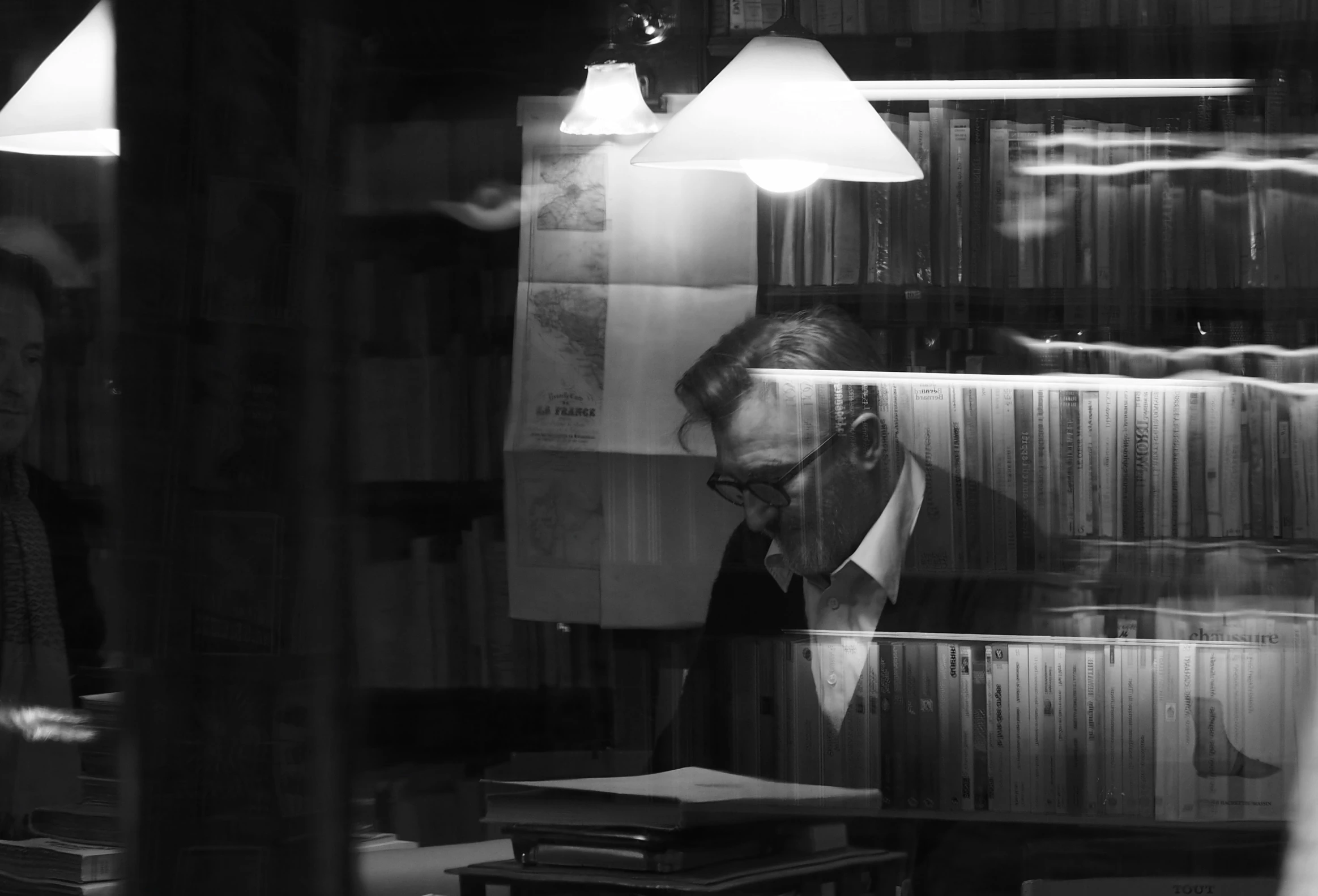 two people in front of some bookshelves looking through the glass