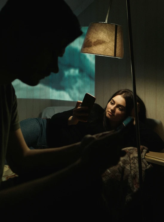 a young man reading a book to a woman sitting in bed