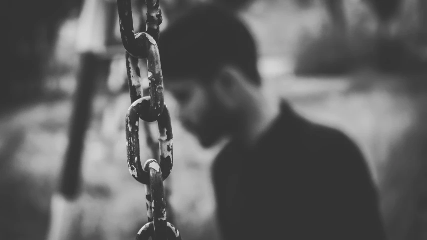 a black and white po of a man in the dark with a long chain across his face