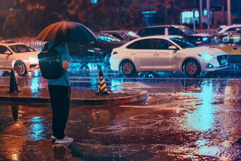 people standing in the rain under umbrellas and cars