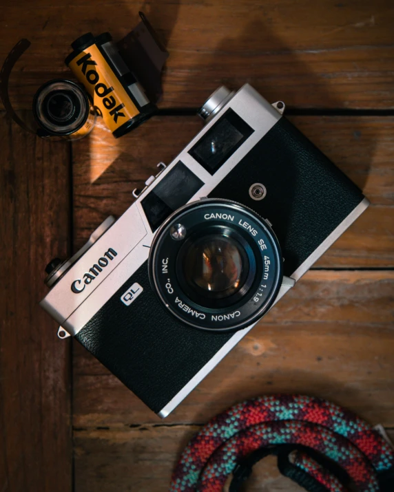 an old camera with a lens, some rope and an orange and yellow camera