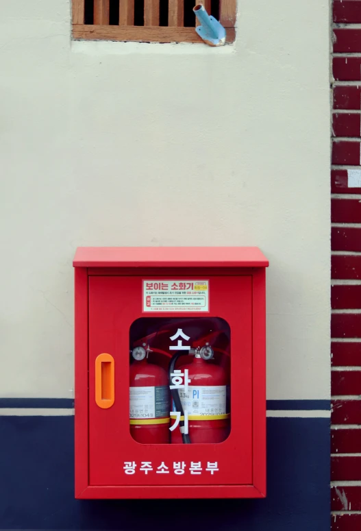 a box with three fire hydrants inside it on the side of a wall