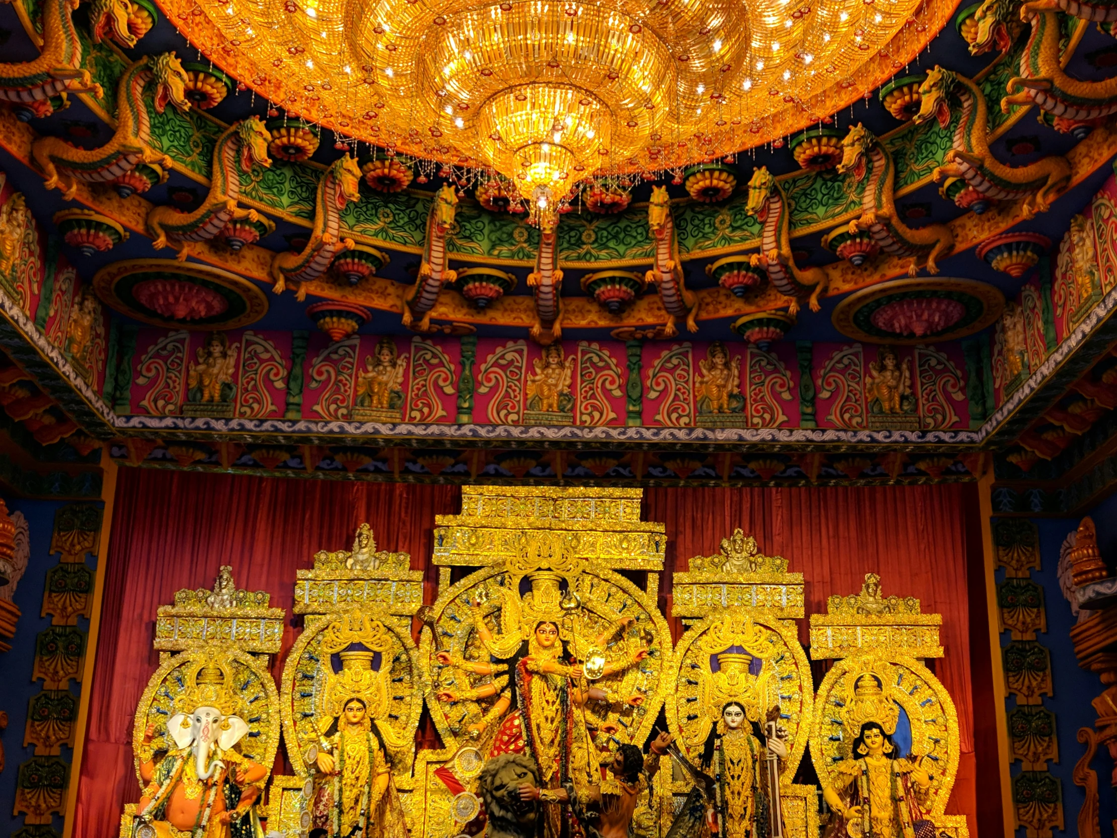 ornate gold decorations and chandelier over red curtain