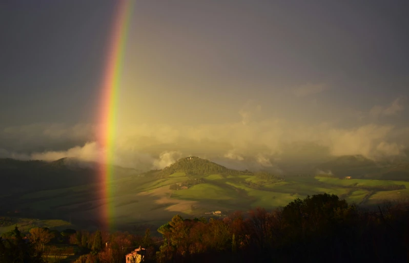 a single rainbow coming out from a distance in the sky