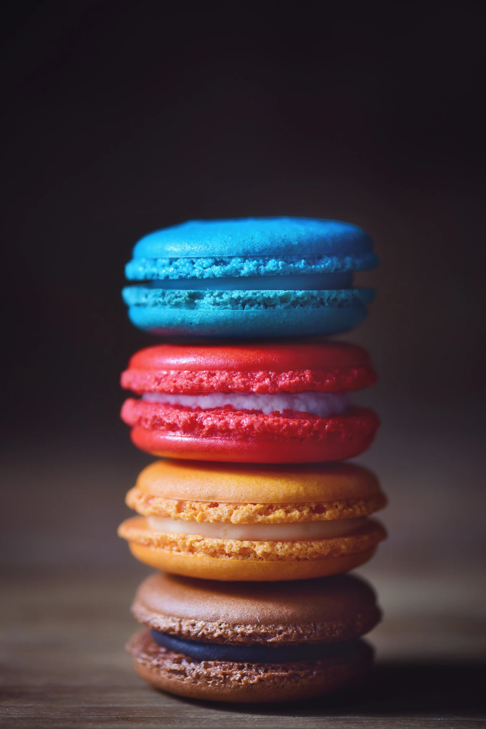 four colorful french macarons sit on the table