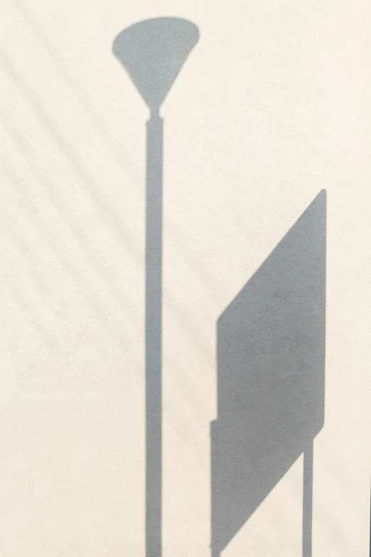 the shadow of a street lamp in front of a stone wall