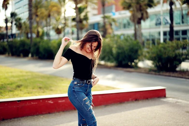 a woman in jeans is standing outside on a skateboard