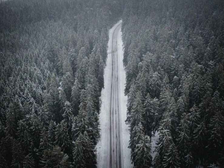 a truck traveling down a snowy road through some trees