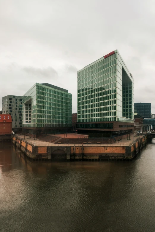 two large green buildings near a body of water