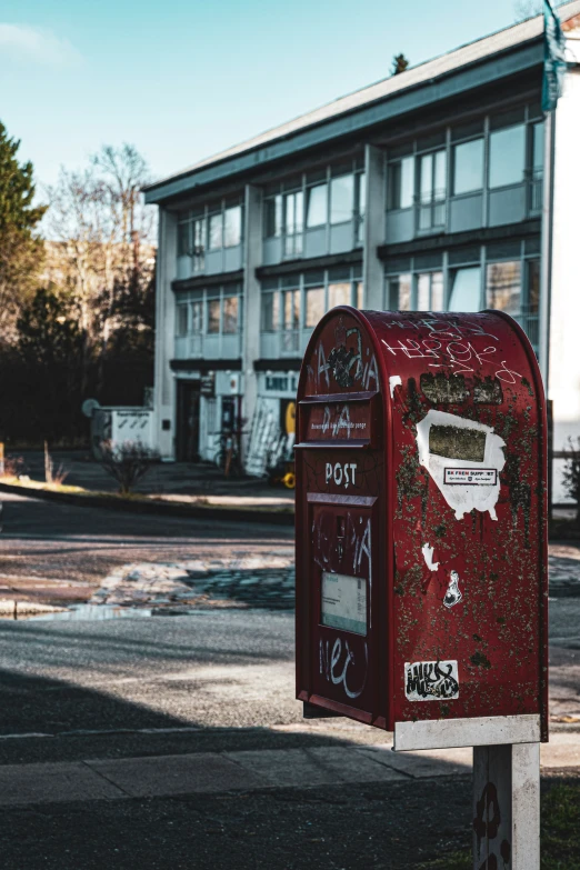 a red mailbox on a sidewalk near a building