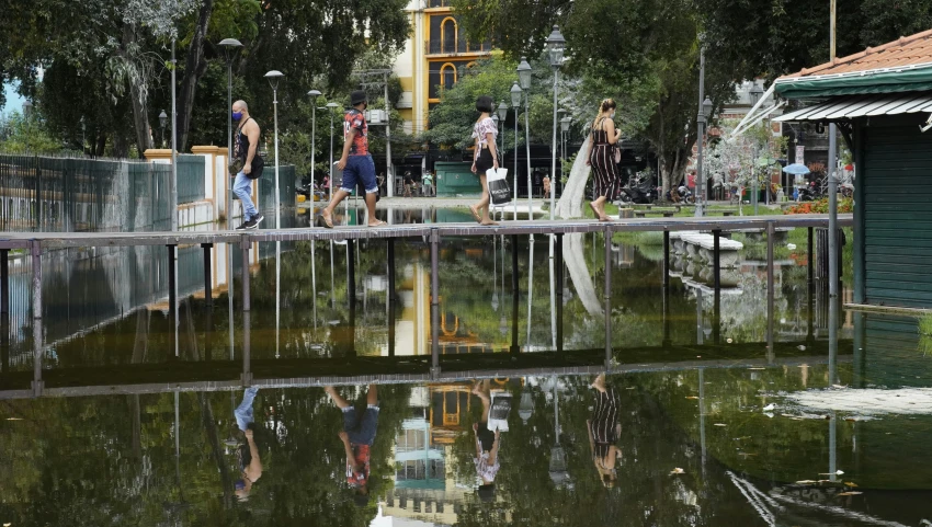 a man and women walking across the bridge that leads to a park