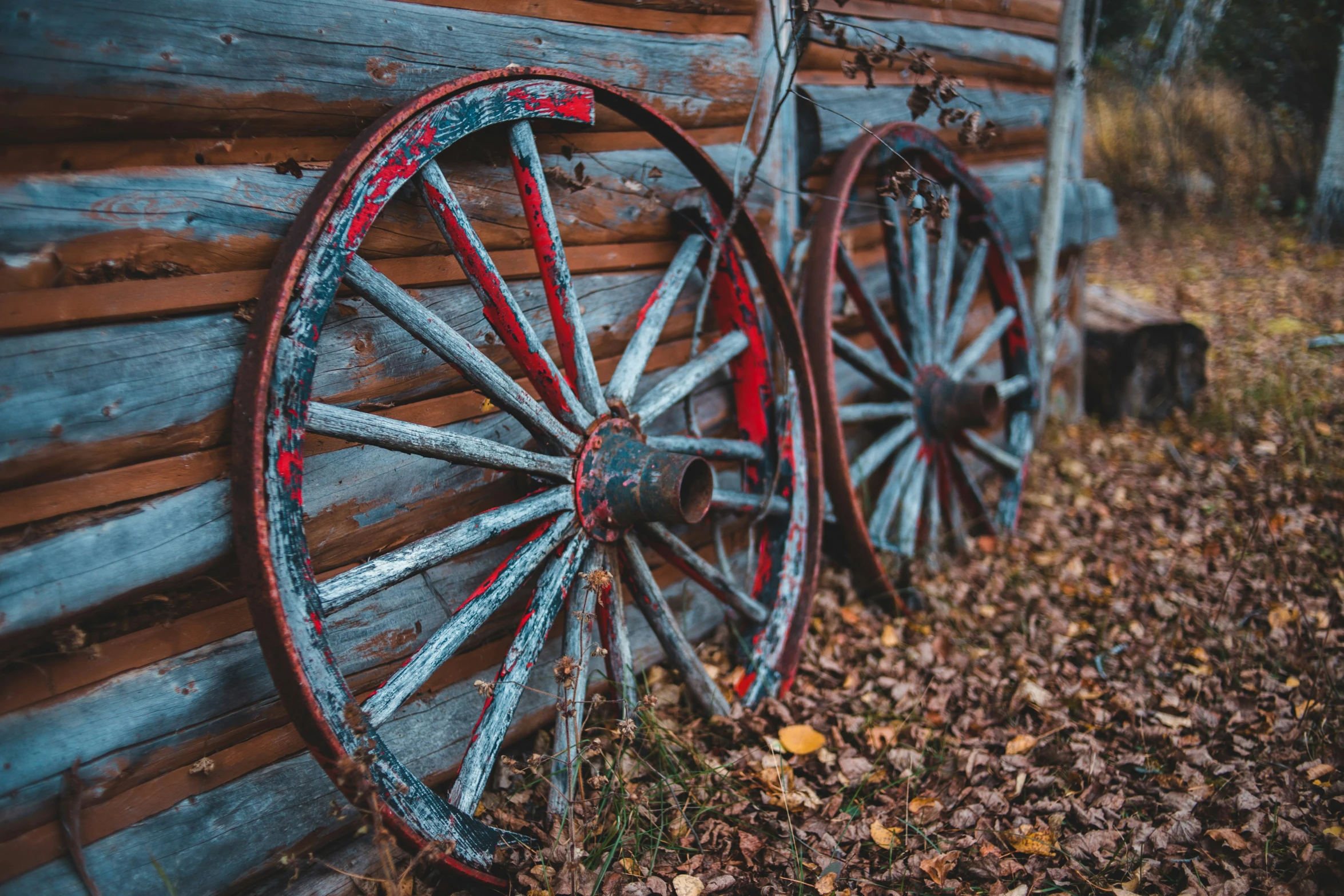 a wagon wheel leaning against the wall of a wooden log house
