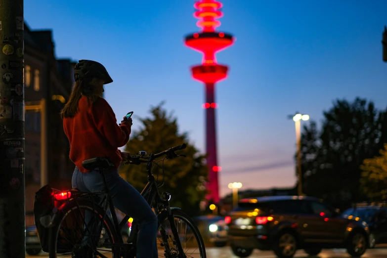 woman on bicycle leaning on pole next to traffic lights