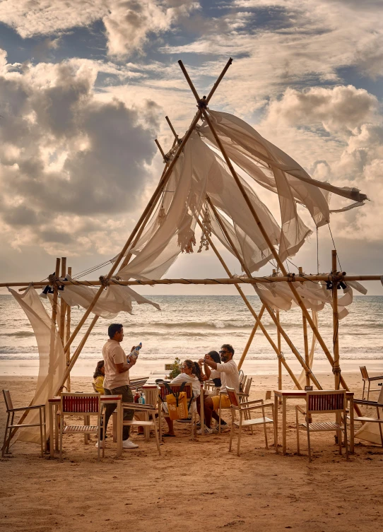 people sitting around an outdoor dining area with water in the background