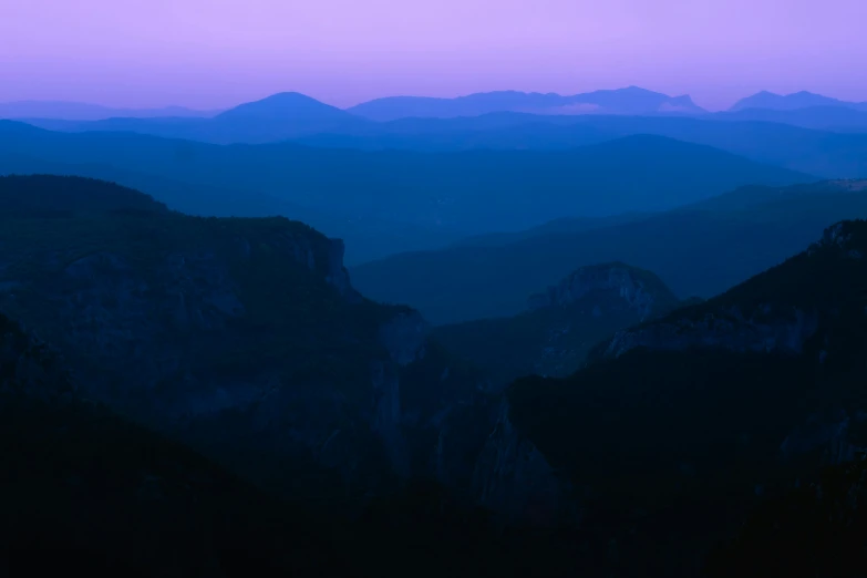 purple and blue light shines through the mountains