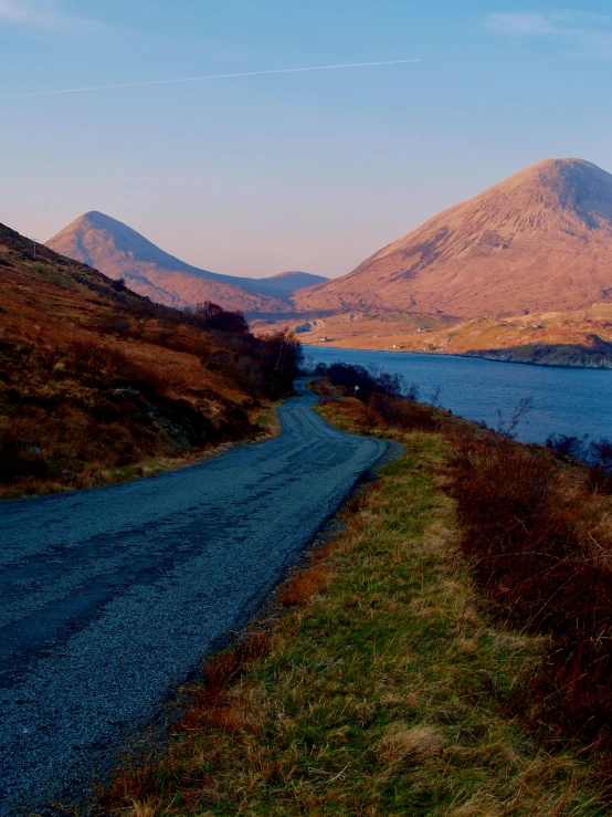 there is a empty road near a mountain lake